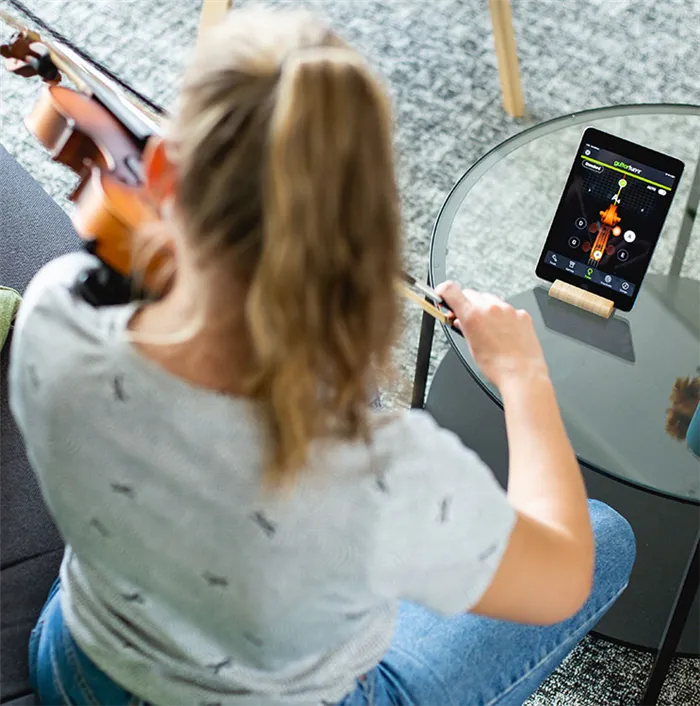 A lady tuning a violin with an mobile app