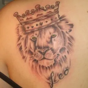Тату на лопатке девушки - лев в короне и надпись