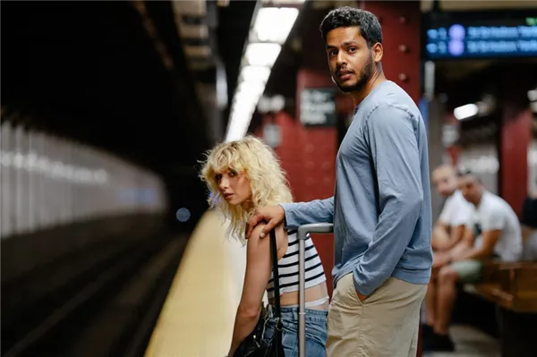 Парень придерживает девушку за плечо в ожидании поезда в метро