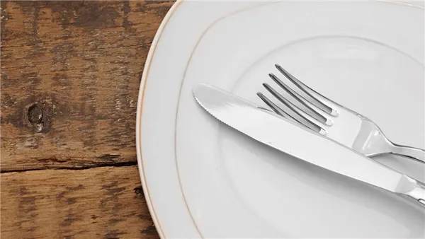Нож с вилкой после еды на тарелке